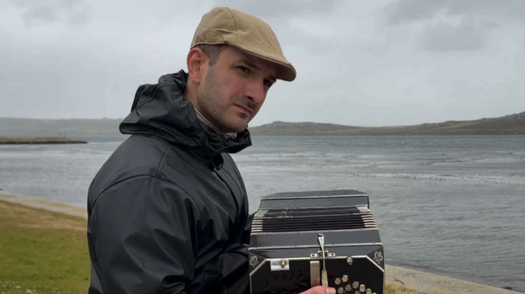 Alejandro Pereyra con su bandoneon frente a la costa de las Islas Malvinas